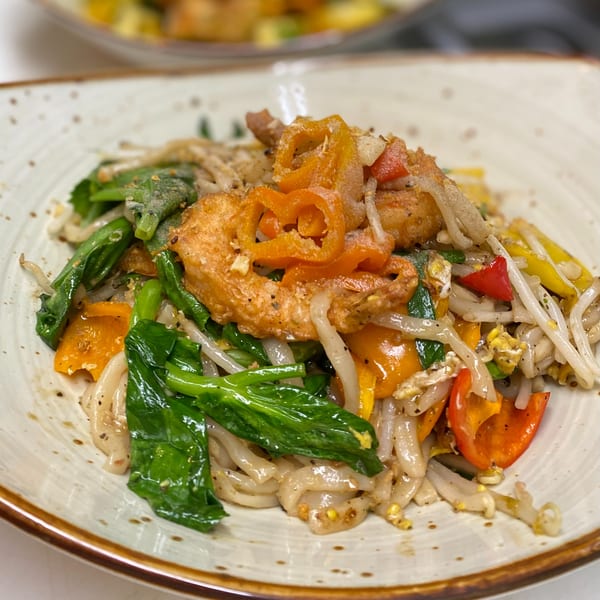 Close-up of Thai Basil's Pad See Ew with wide noodles, chicken, broccoli, and bell peppers.
