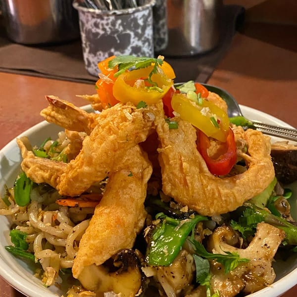 Crispy fried shrimp and colorful bell peppers atop a bed of Thai noodles and vegetables.
